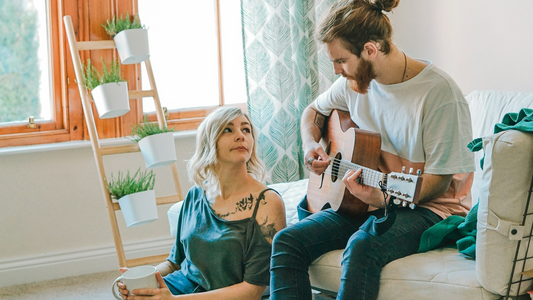 Man playing guitar to girlfriend after fighting, red flags in relationship