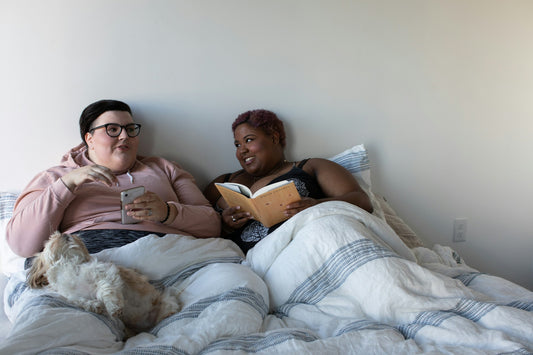 BIPOC queer couple enjoying feeling emotional safety together while chatting in bed
